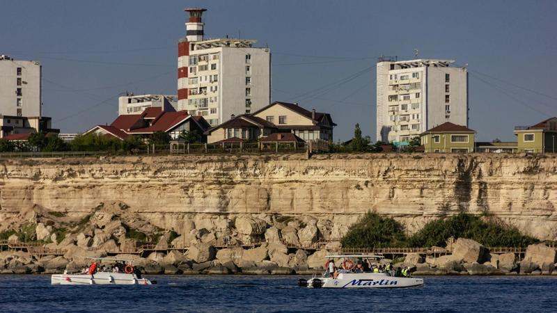 Скалистый берег Каспийского моря в Актау — слоистые жёлтые обрывы, бирюзовые волны и набережная с фонарями