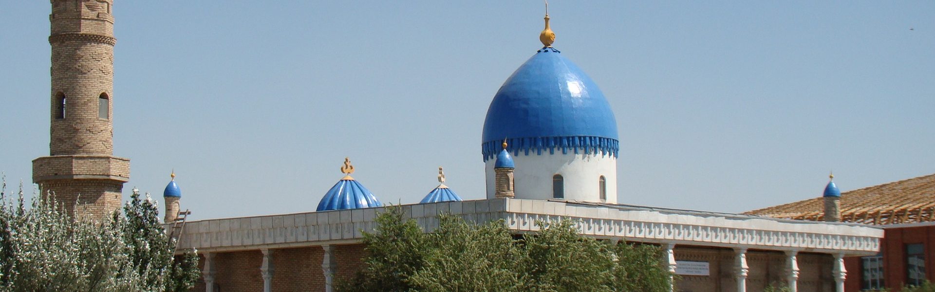 Мечеть Айтбай в Кызылорде — кирпичный минарет и небесно-синие купола над зелёной листвой