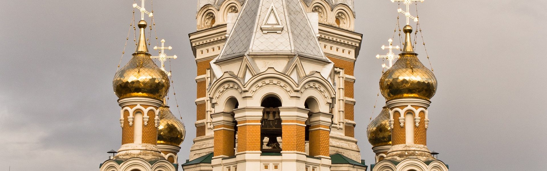 Храм Христа Спасителя в Уральске — золотые купола и крестовый узор кирпичной кладки на фоне неба